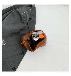 Detail view of brown faux leather inner pouch with gold zipper and cosmetic storage space