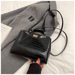 Détail d'un sac à main noir motif crocodile avec fermoir rotatif doré en similicuir