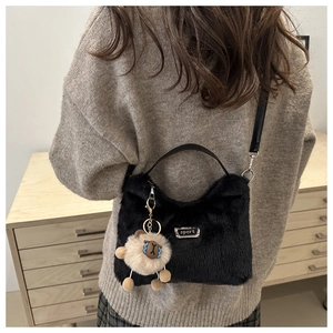 Détail d'un sac bandoulière en peluche noire avec lanière en cuir et breloque mouton