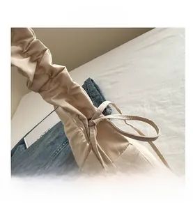 Detailed view of beige nylon tote bag featuring adjustable drawstrings and pleats