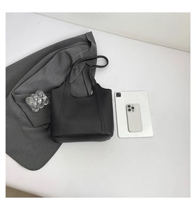 Minimalist black leather tote bag shown from above with office accessories and blazer