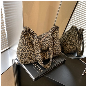 Detail of leopard print canvas tote bag featuring adjustable bronze metal buckle and zipper