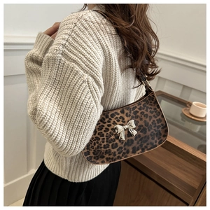 Detail of leopard print handbag with silver metal bow and leather shoulder strap