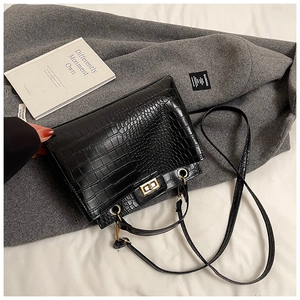 Détail d'un sac à main noir à texture crocodile avec fermoir rotatif en or vieilli