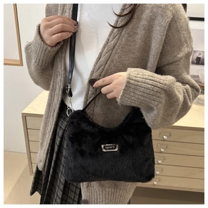 Gros plan du sac croissant en peluche noire avec plaque métallique et fourrure synthétique