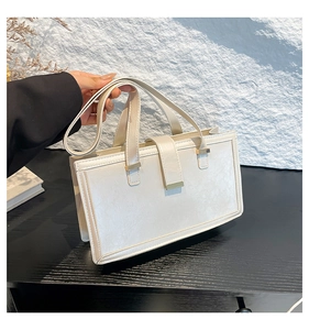 Detail einer cremeweißen Lederhandtasche mit goldfarbenen Beschlägen und Tragegriffen
