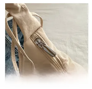 Close-up of smooth silver metal zipper on light beige nylon pleated cloud bag