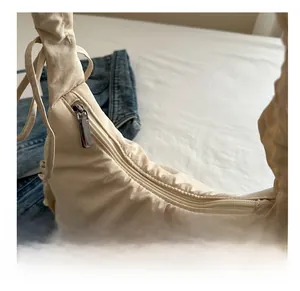 Detail of ruched drawstring shoulder strap on beige nylon tote bag with metal zipper