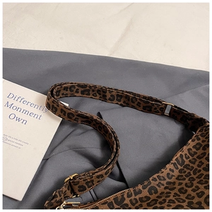 Close-up of leopard print canvas tote with adjustable strap and vintage metal hardware