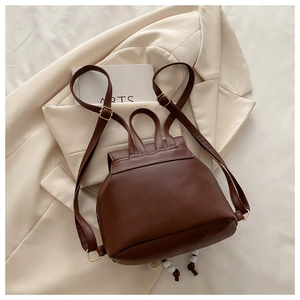 Brown faux leather backpack detail with adjustable strap and white bead tassel accessory