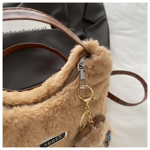 Détail du sac à main en peluche kaki avec fermeture éclair argentée et pendentif ours