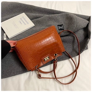Détail du sac en cuir marron à motif crocodile avec fermoir rotatif en métal doré