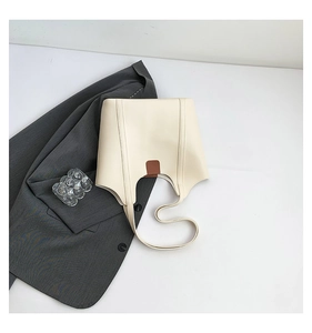 Close-up of minimalist cream tote bag featuring a contrasting brown leather patch detail