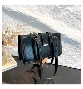 Detailansicht der glänzenden schwarzen Schultertasche mit Knitteroptik und Metallschnalle