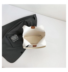 Detailed interior of minimalist beige tote bag with brown leather magnetic closure and zip pocket