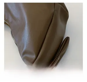 Detailed close-up of brown textured leather crescent bag with smooth metallic zipper finish