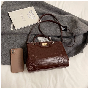 Détail du sac en cuir marron foncé à texture crocodile avec fermoir doré et poignée fixe