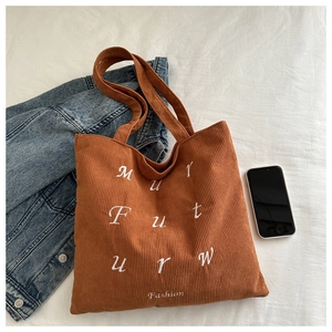 Detail of warm brown corduroy tote bag showing soft ribbed texture and letter embroidery