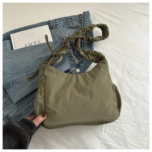 Detail of nylon cloud bag with ruched shoulder strap and side drawstring bow accent