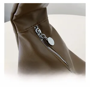 Detailed close-up of smooth silver metal zipper and stitching on brown PU leather bag