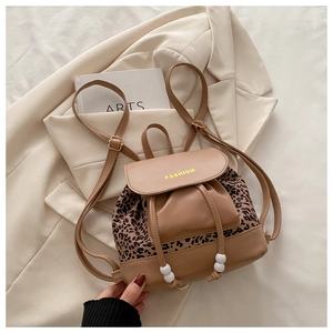 Détail du sac à dos léopard avec rabat magnétique et accessoire boule blanche