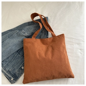 Detailed texture of brown corduroy tote bag showing vertical ribbed fabric and wide straps