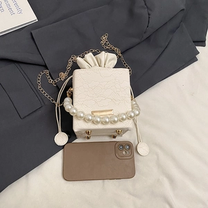 Detailed shot of white lace texture handbag with pearl handle and golden chain
