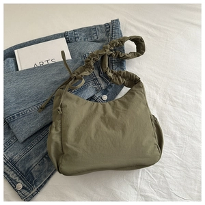 Detail of olive green nylon dumpling bag featuring a pleated shoulder strap and drawstring