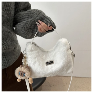 Détail du sac à main en fausse fourrure blanche avec plaque sport et breloque ours