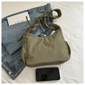 Detail of olive green nylon tote bag with pleated cloud strap and drawstring accents