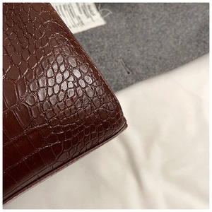 Macro shot of dark brown crocodile embossed leather texture with precise edge stitching