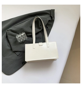 Detail der weißen rechteckigen Schultertasche aus Leder auf einem grauen Blazer
