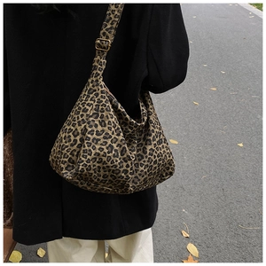 Outdoor street view of a leopard print canvas hobo bag with adjustable strap and autumn vibe