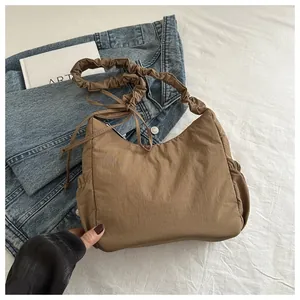 Detail of coffee brown nylon hobo bag featuring pleated straps and drawstring design