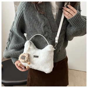Détail d'un sac bandoulière en peluche blanche avec plaque sport et breloque mouton brun