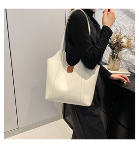 Detail of minimalist cream tote bag showing brown patch accent and smooth faux leather texture