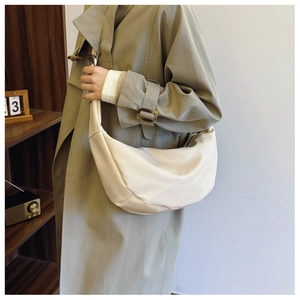 Detail of minimalist beige half-moon hobo bag showing soft leather texture and sleek design