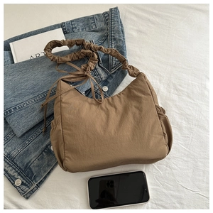 Detailed view of caramel nylon hobo bag with scrunched strap and drawstring details
