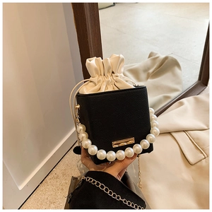 Detail of black pebbled PU leather handbag with pearl handle and gold chain strap