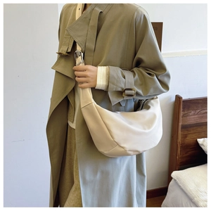 Detail of minimalist beige crescent crossbody bag with adjustable wide shoulder strap