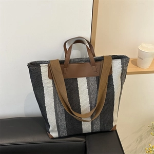 Minimalist striped canvas tote bag with brown leather handles on a modern sofa