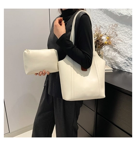 Detail of a large cream tote bag with a matching pouch shown on a person shoulder