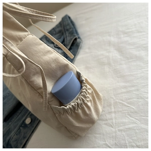 Detail view of nylon drawstring cloud bag showing side pocket holding a water bottle