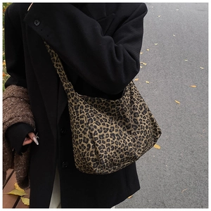 Close-up of leopard print canvas tote bag styled with a black coat in an autumn street setting