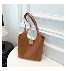 Close-up of caramel brown tote bag with premium matte leather texture and gold buckle