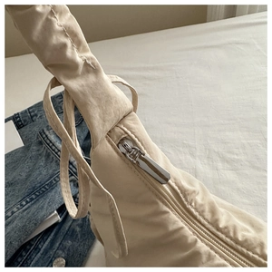 Close-up of apricot nylon bag with pleated texture and adjustable shoulder strap detail