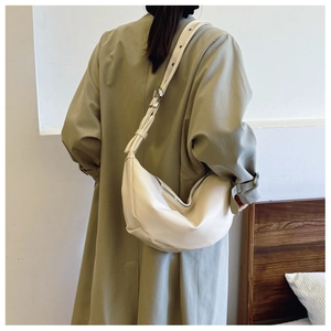 Detail of beige crescent underarm bag with silver hardware and eyelet strap on model