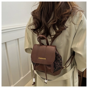 Rear view of a stylish brown faux leather backpack with leopard print side panels and charms