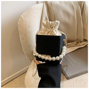 Detail of black and white leather mini bag with large pearl handle and gold chain strap