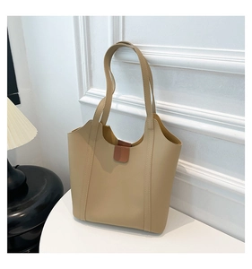 Detail of minimalist beige tote bag showing scalloped edge and brown magnetic closure